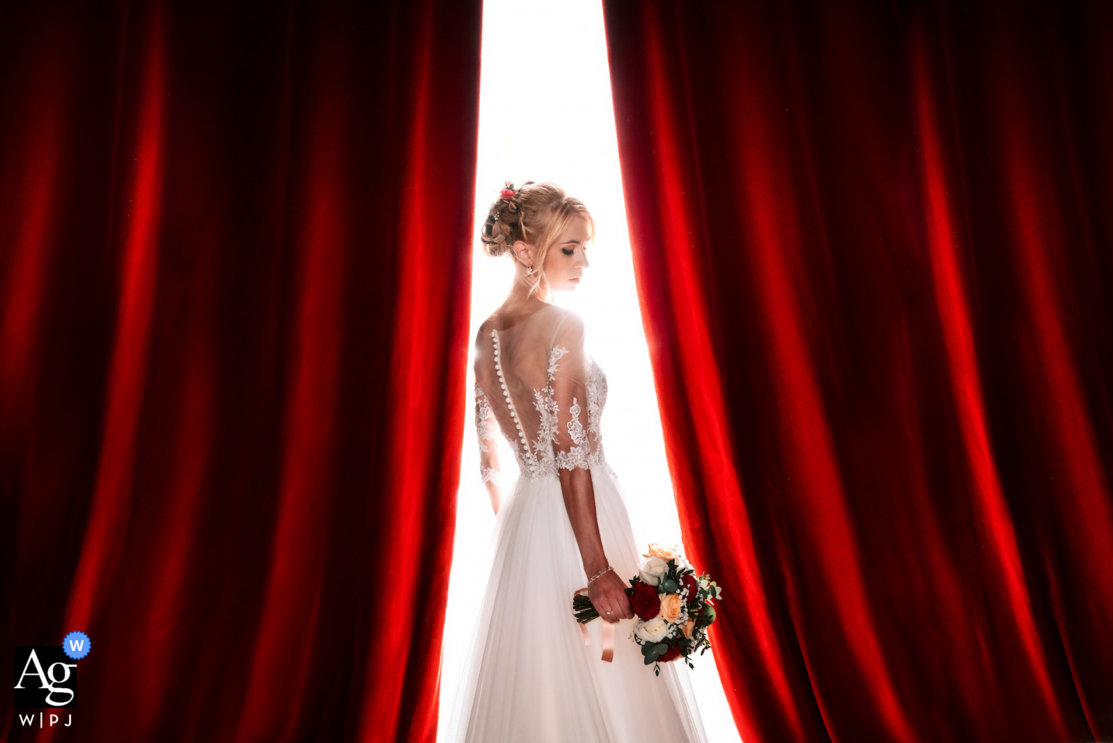 View this elegant Occitanie wedding image of a Bride and a red curtain, which was a featured picture among the best wedding photography at Chateau de Launac from the WPJA