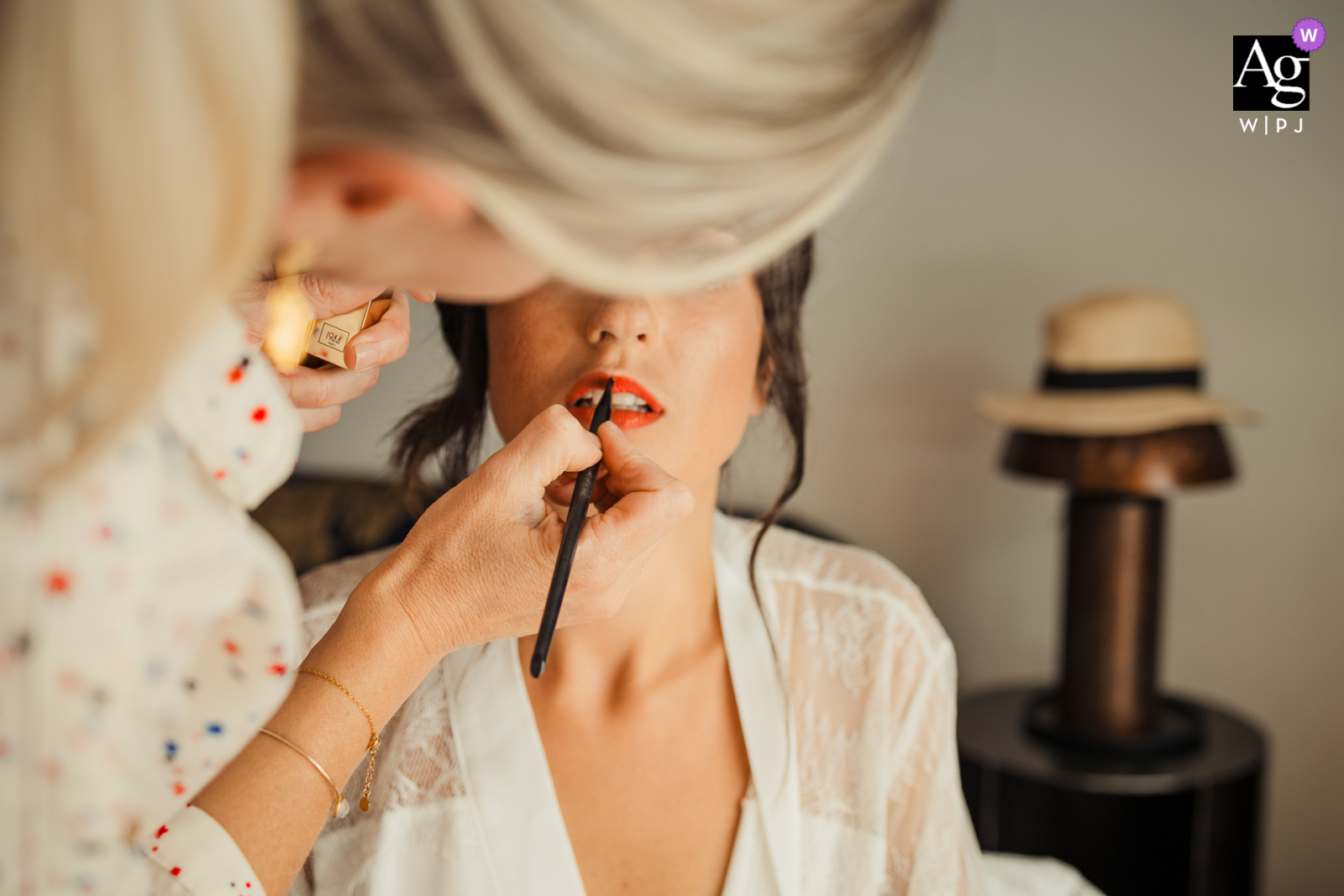 Regardez cette image de mariage de bon goût du Domaine des Grillions illustrant que la maquilleuse met le rouge à lèvres sur la mariée, qui figurait parmi les meilleures photographies de mariage dans la Drôme provinciale, en France, de la WPJA