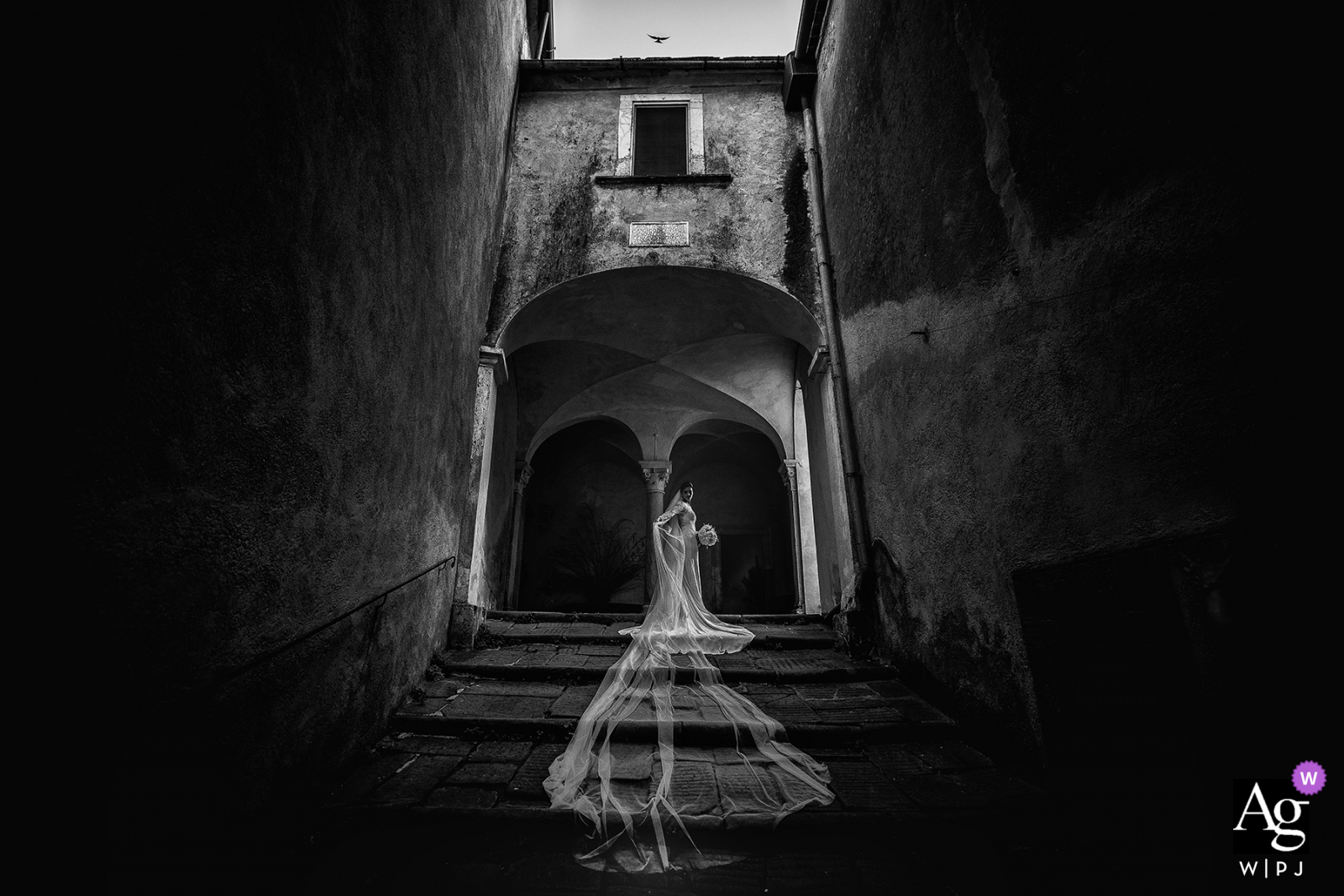 World's most artistic BW wedding photography from Castello Malaspina Massa of The bride at the top of the steps with her veil flowing down behind her