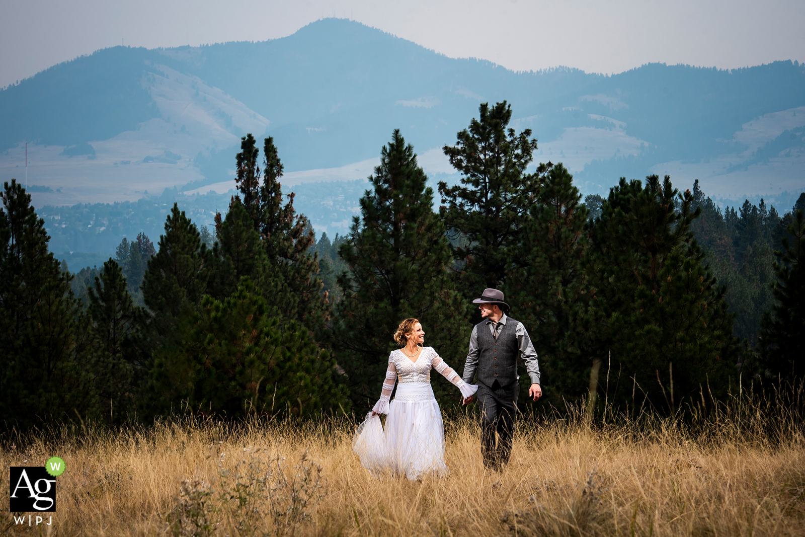 Ein ausgewähltes Blue Mountain-Hochzeitsporträt eines Missoula-Paares in Montana, das durch eine Bergwiese schlendert