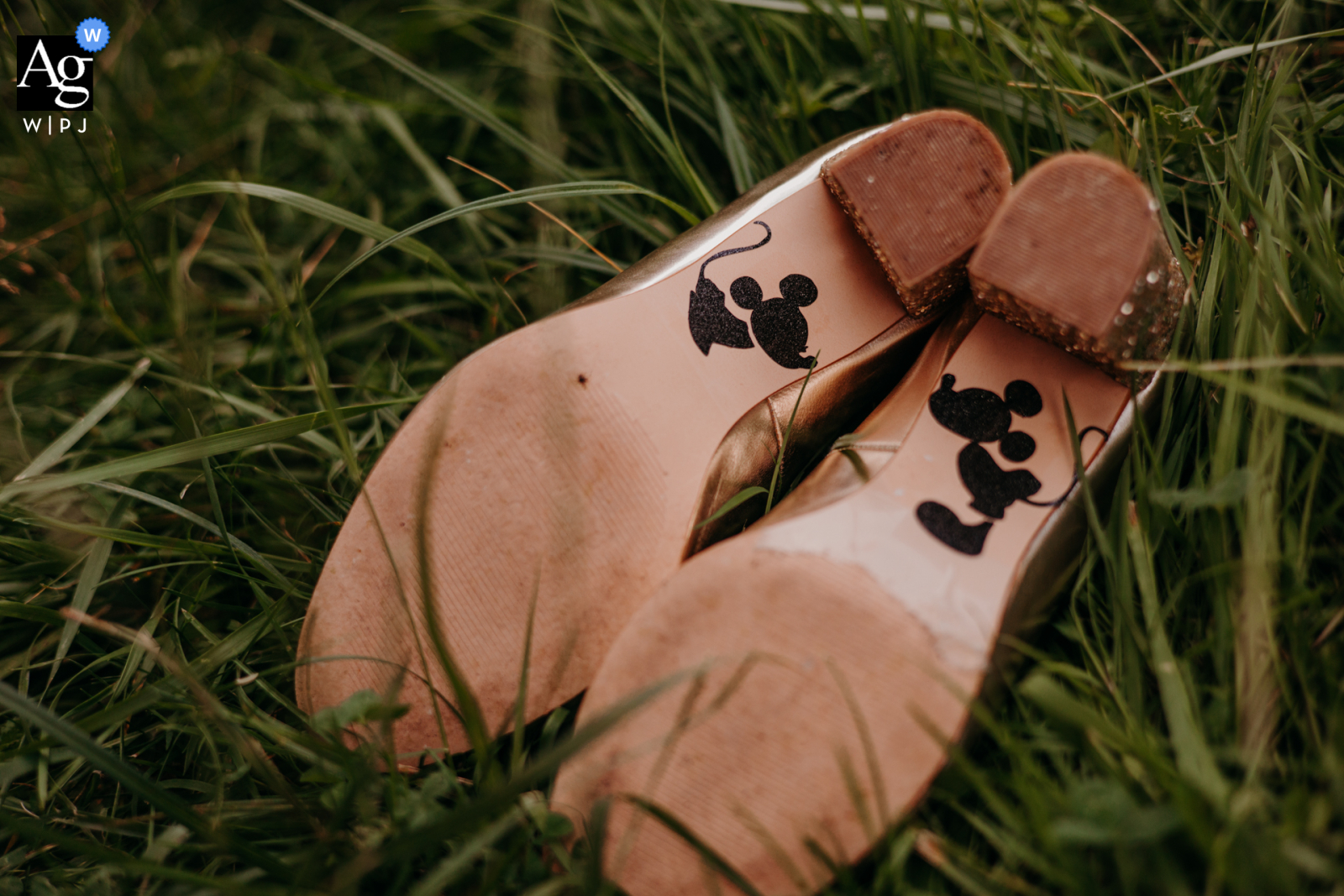 Ein Detailbild zum rustikalen Hochzeitstag in Frankreich, das Mickey und Minnie auf der Unterseite der Schuhe im Gras zeigt