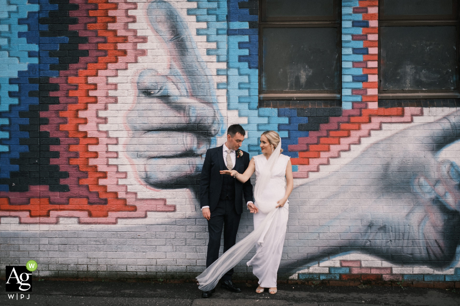 Ein spektakuläres Hochzeitspaarfoto aus Nordirland in Central Belfast vor einem Stück beliebter Straßenkunst, das auf die Gebäudewand gemalt wurde