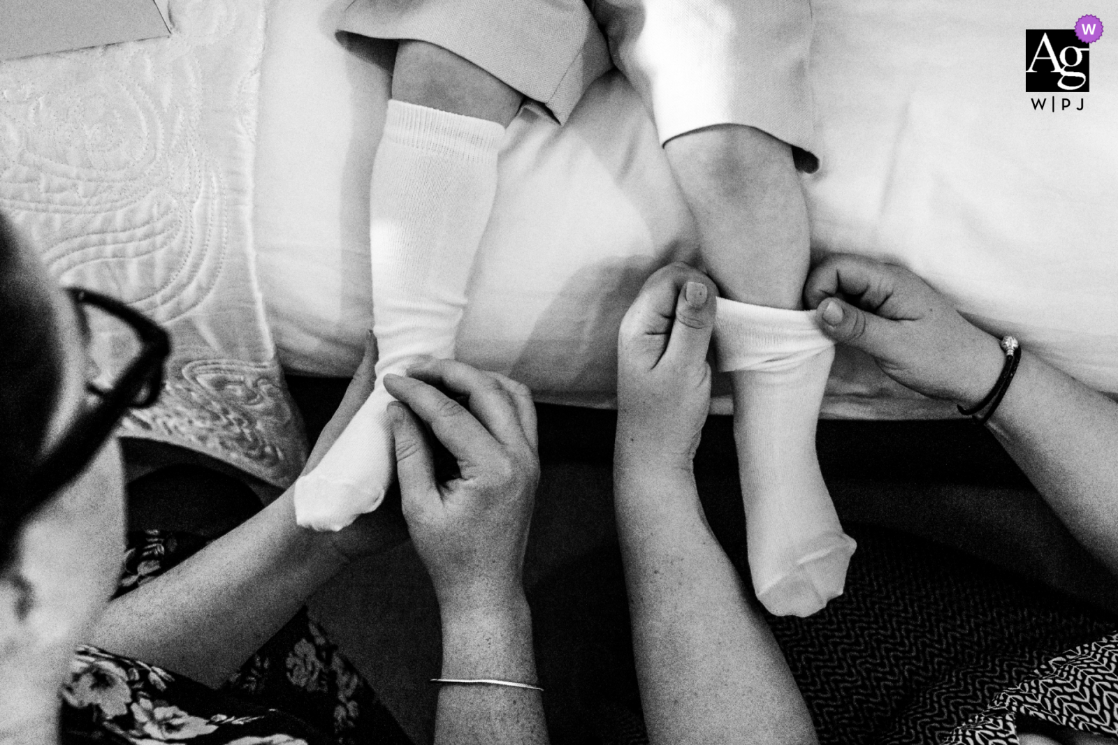 Une photo du lieu de mariage de Hodsock Priory dans le Nottinghamshire en BW de deux invités aidant le page boy à mettre ses chaussettes