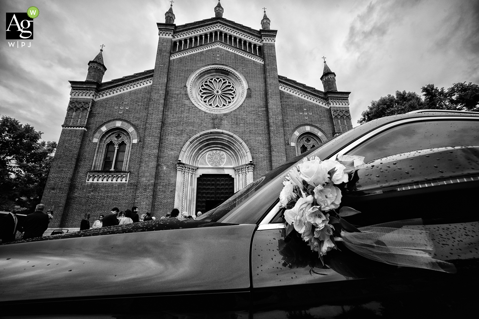 The exterior of the Church of Saints Giuseppe and Floriano in Verderio (Lc) is seen from behind the bride and groom's car in a black and white image