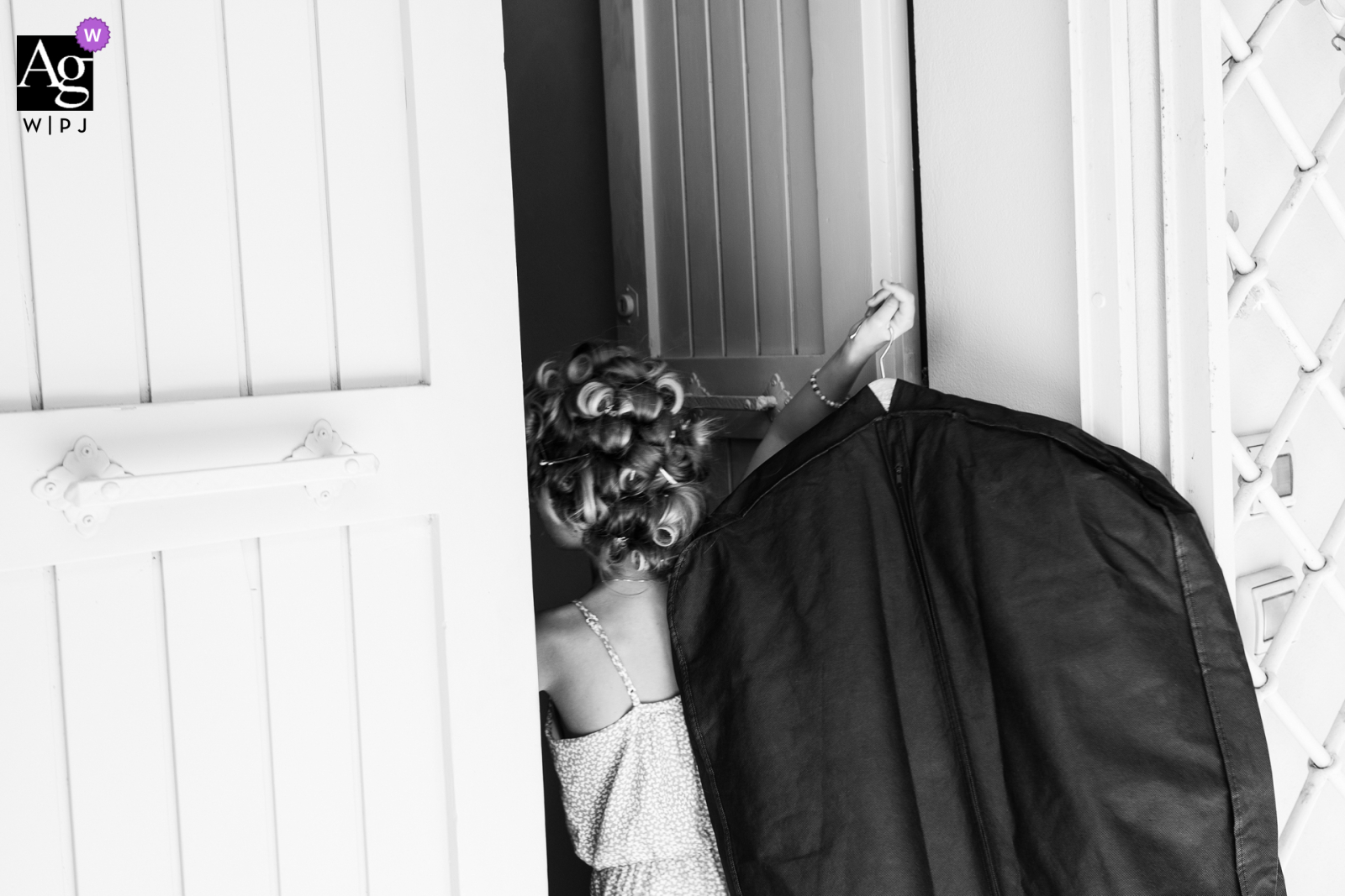 A Pisa wedding photographer created a charming BW image of a small bridesmaid transporting the bride's dress into her room ahead of the ceremony