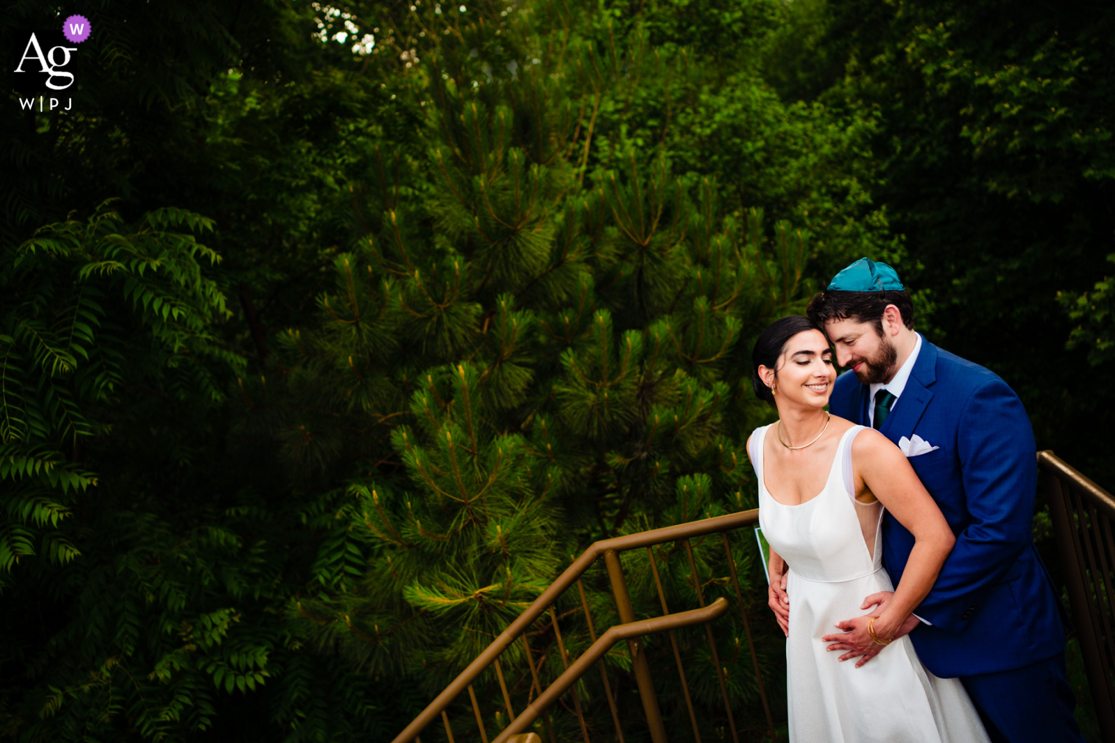 A couple embraces on a rooftop garden in Roswell, Georgia for a creative wedding portrait, with green foliage providing a scenic backdrop