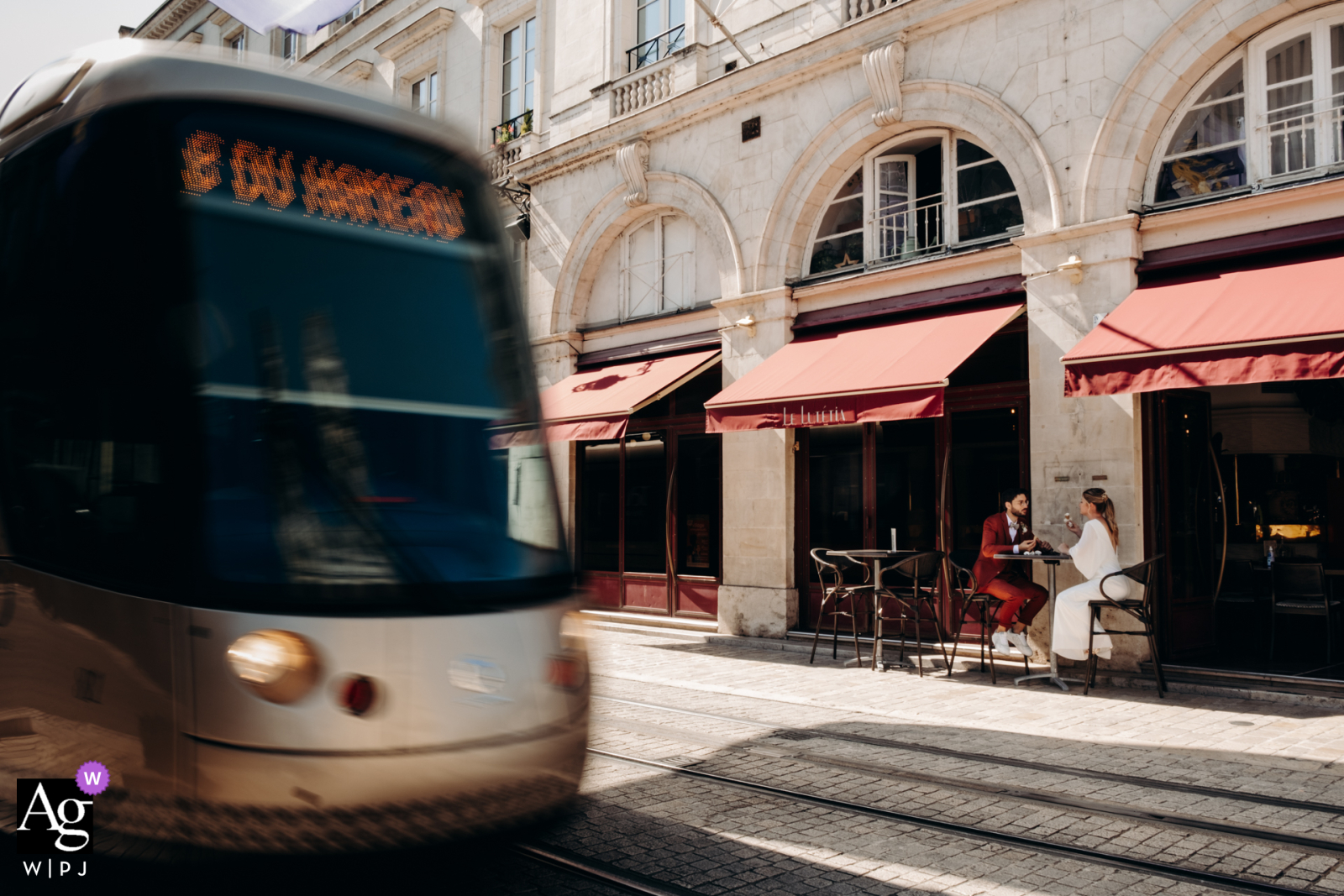 At Rues d'Orléans, the newlyweds are seated at a sidewalk cafe table, photographer captured the blur of a passing bus with a slow shutter