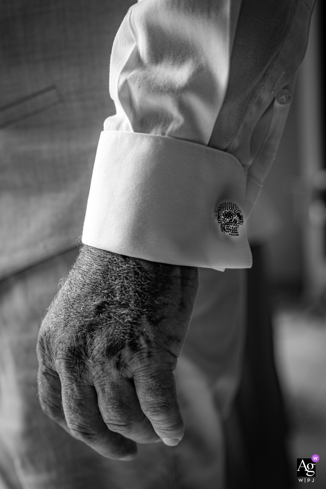 In a masterful display of artistry, a wedding photographer captures the intricate beauty of the groom's cufflinks and hand in black and white at Saint Sauvant.
