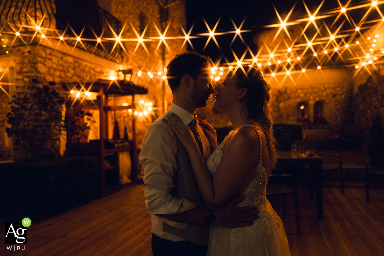 At Bastide de Jaillans, as the evening draws to a close, the couple embrace after a night of dancing. Starbursts form above them from the many string lights overhead.