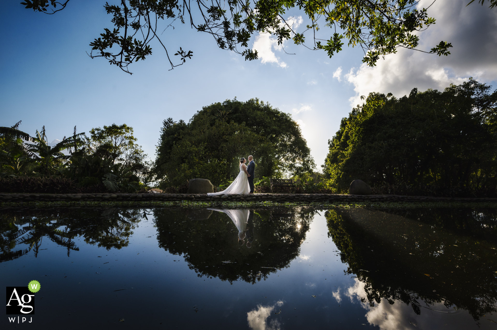 Bride and groom reflected in the lake at their wedding venue, Finca Vikingos, Heredia, Costa Rica. 