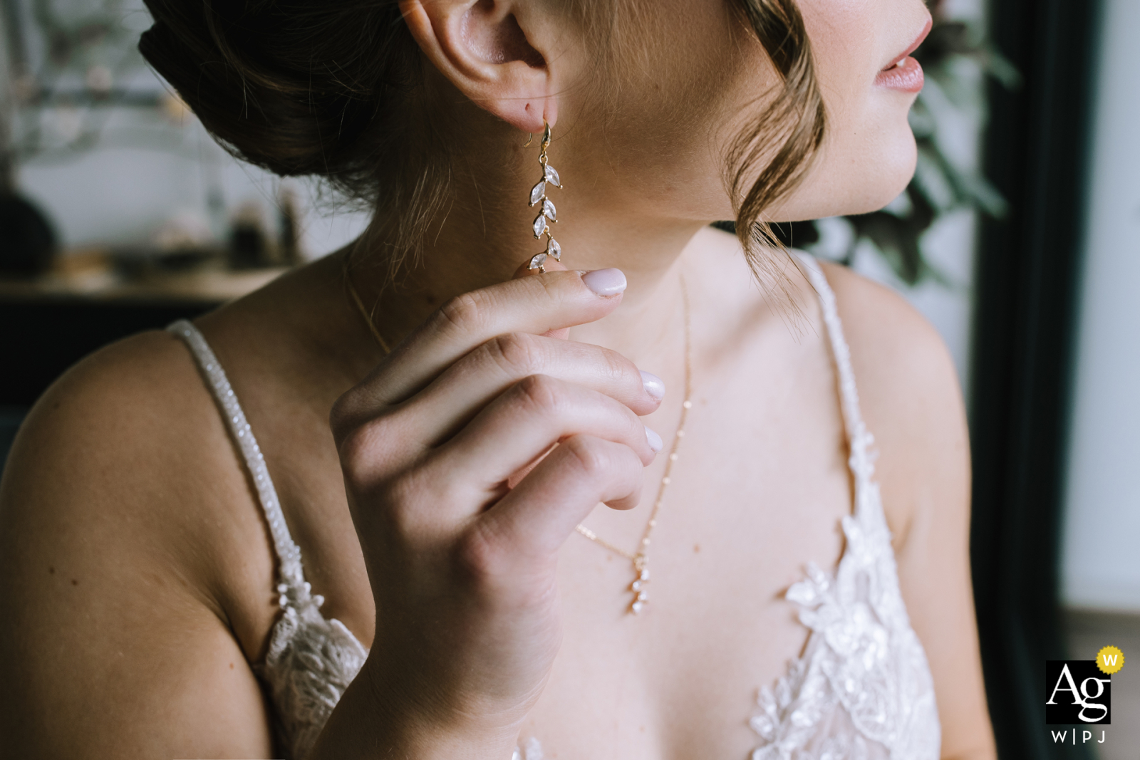 In Schalksmühle, Sauerland, Germany, a tightly cropped profile shot captures the bride as she carefully puts on her earrings, highlighting the elegance and anticipation.