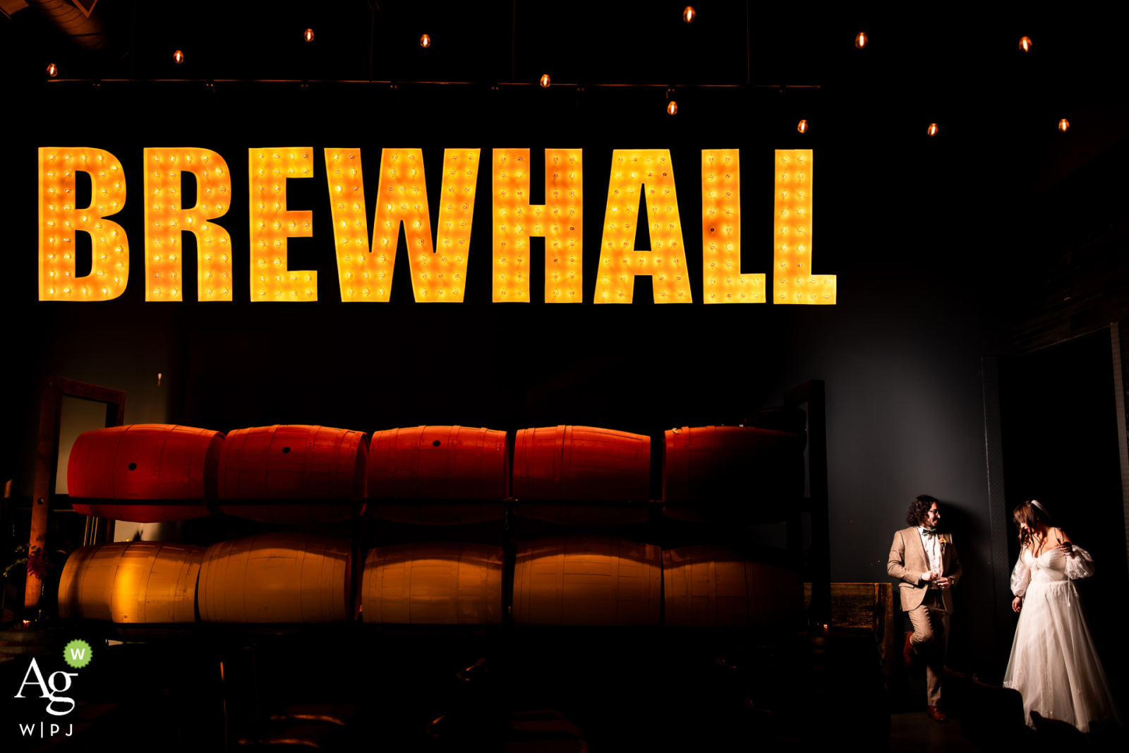 Newlyweds pose joyfully beneath the Amsterdam Brewery sign, celebrating their love amidst industrial chic charm
