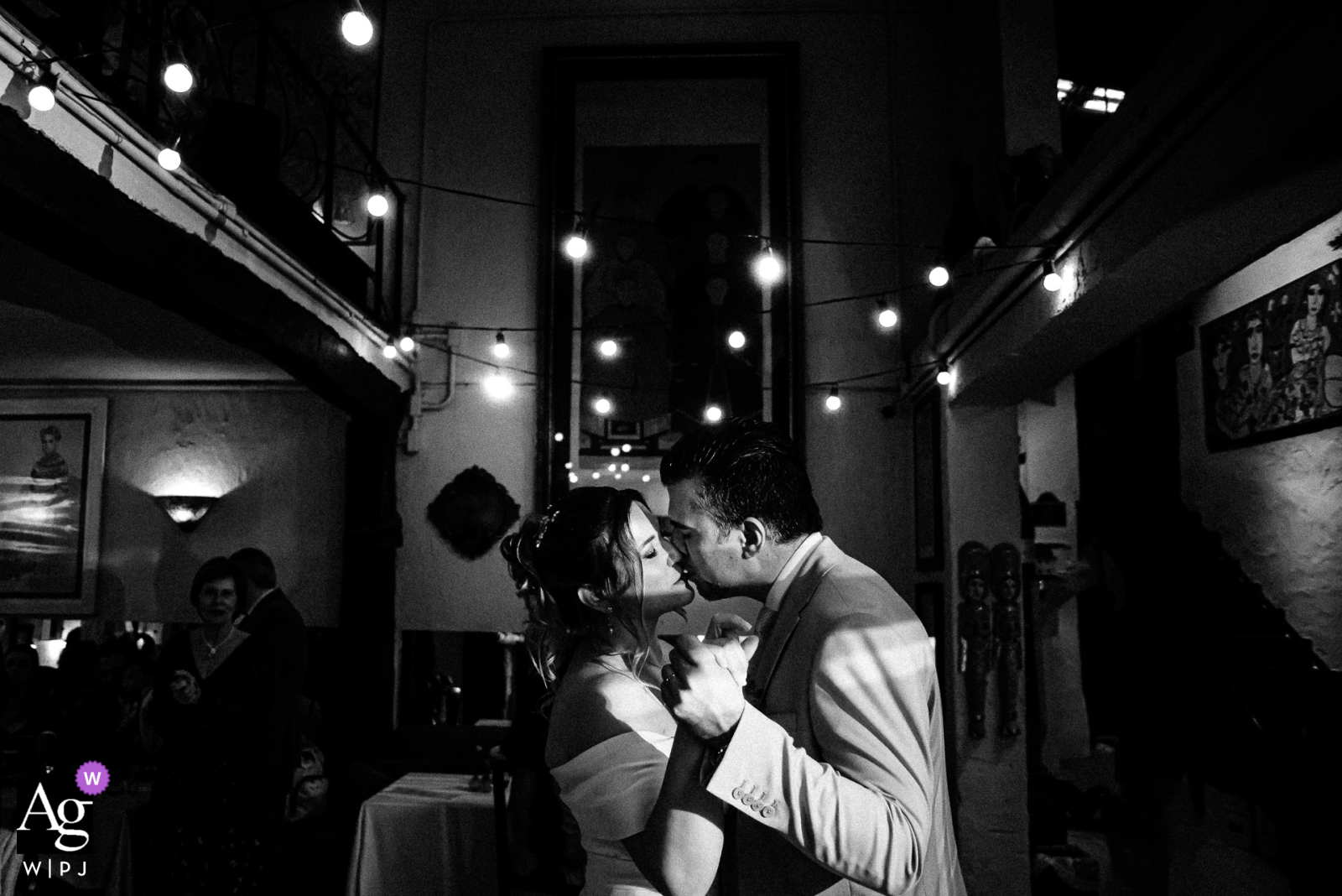 At Ruella Bistrô in São Paulo, Brazil, a black-and-white portrait captures the couple sharing a kiss as they dance inside the restaurant, with light and shadows artfully playing across the scene.
