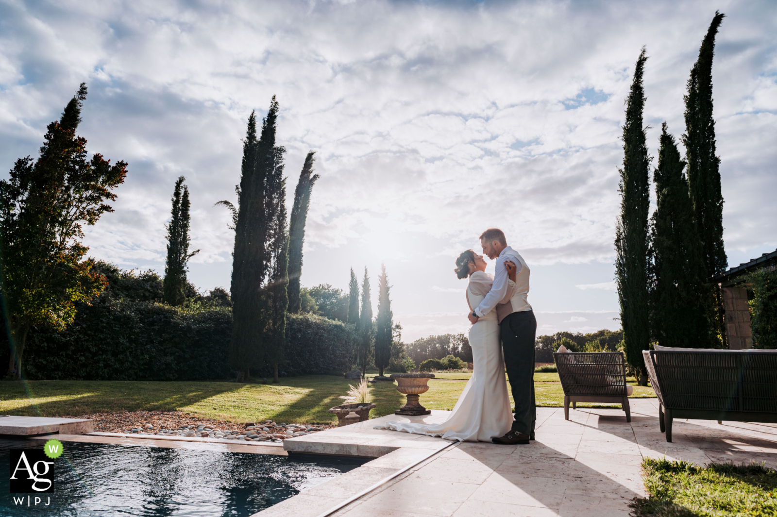 Newlyweds pose in Châteauroux, a serene portrait by a pool, framed by towering trees