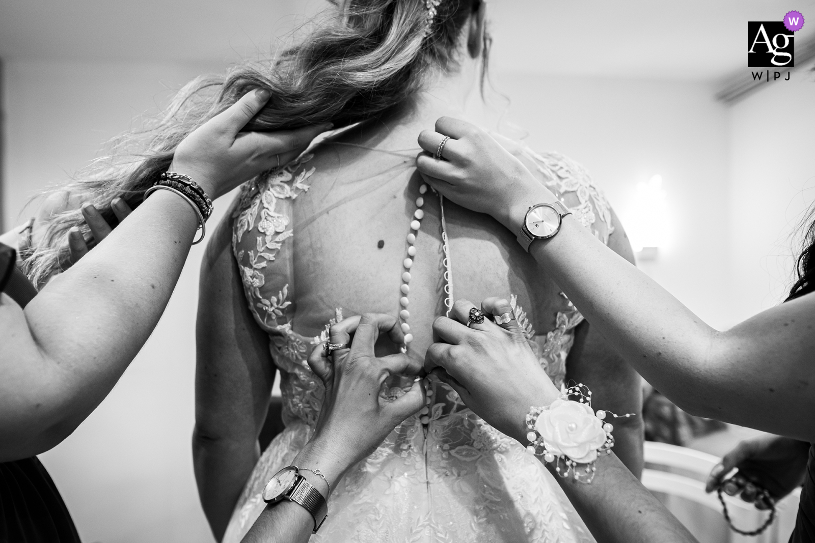 In Mauguio, a black-and-white shot captures the hands of three women as they assist in closing the bride's dress. This intimate image highlights the supportive and collaborative effort of the bride's witnesses as they help her prepare for her special day.
