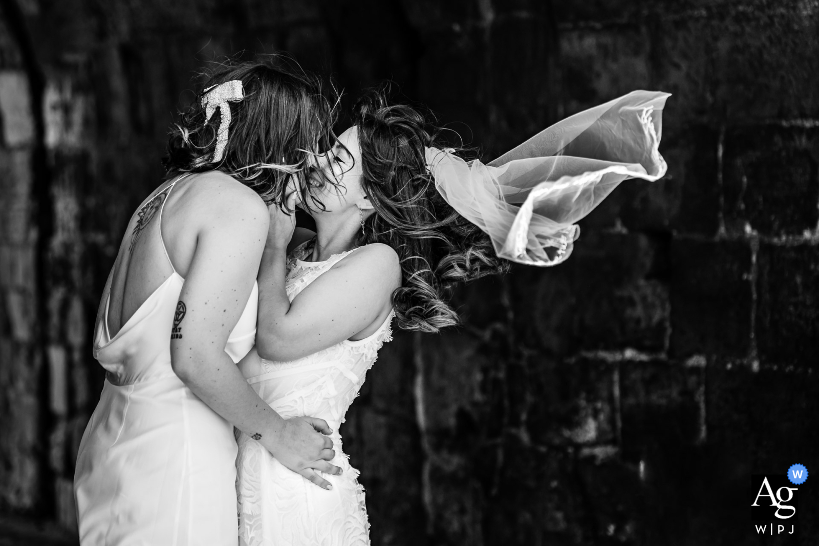 In Portsmouth, a black-and-white shot captures the couple sharing a kiss as the veil gracefully blows in the wind, adding a timeless and romantic element to the photograph.