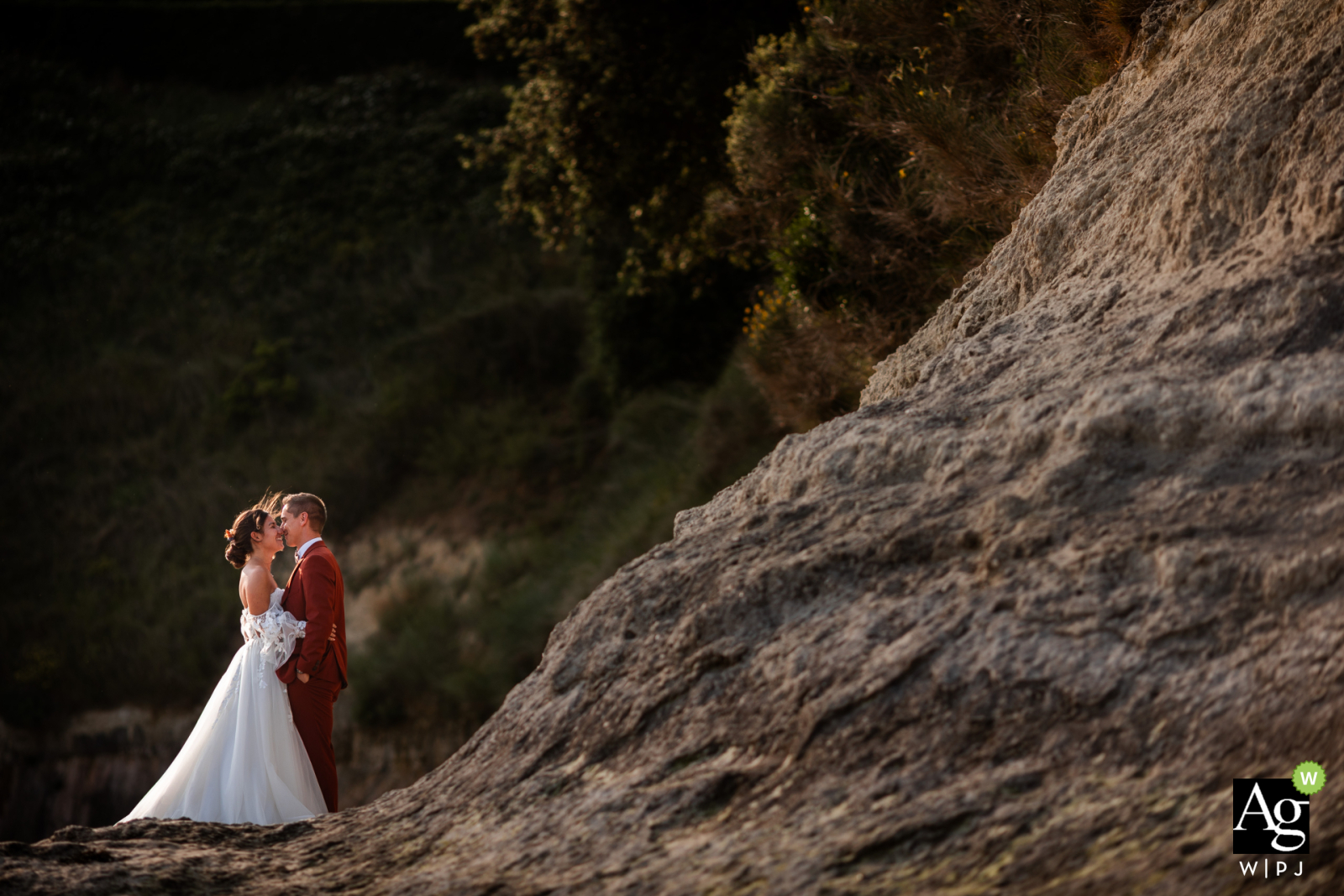 The bride and groom pose for a dramatic portrait on the edge of a cliff in Meschers-sur-Gironde, France, overlooking the vast waters of the estuary during their session.