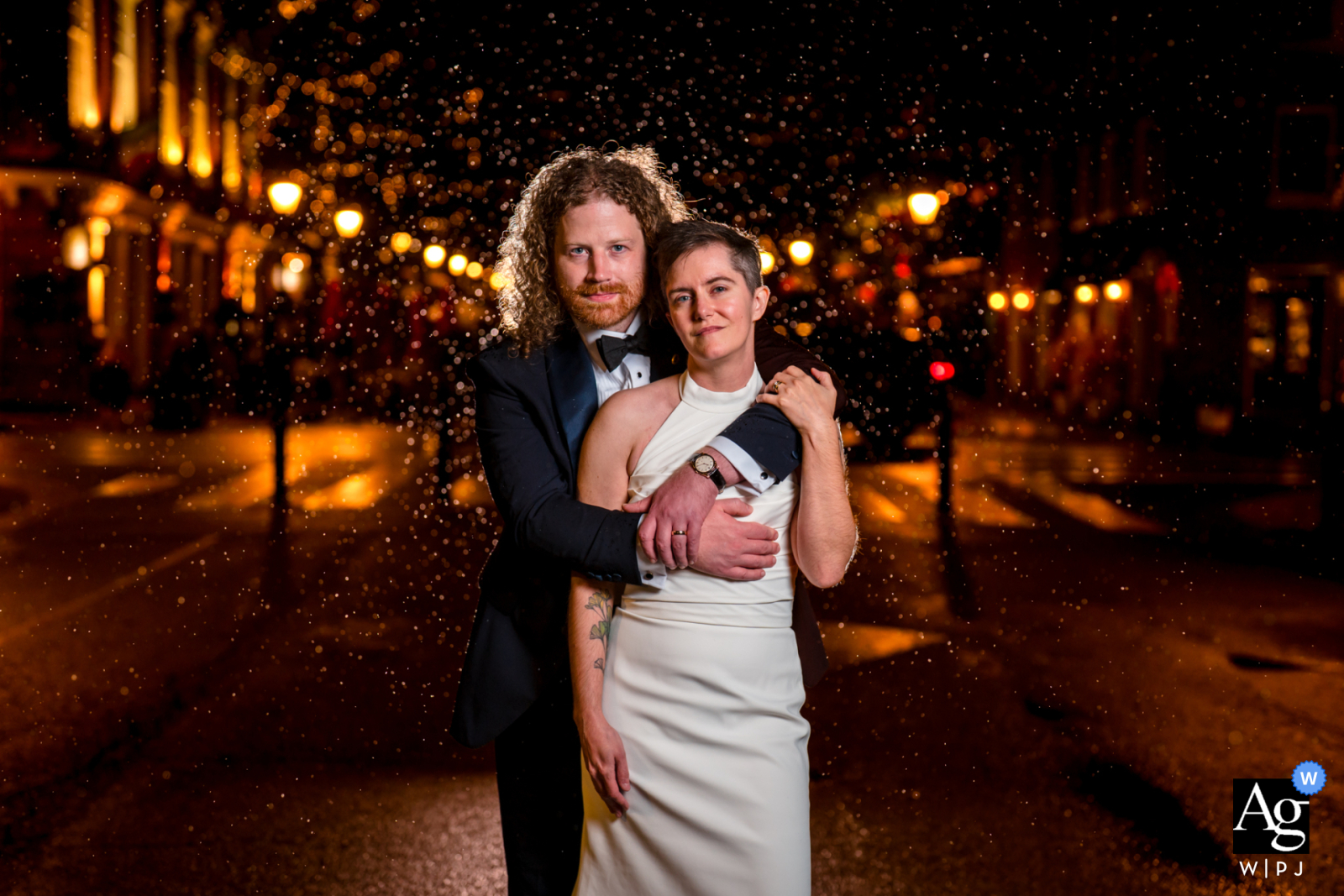 Arlington, VA — The groom embraces the bride in the rain on urban streets near the reception venue, dramatically lit by the photographer to create a romantic and atmospheric wedding portrait.