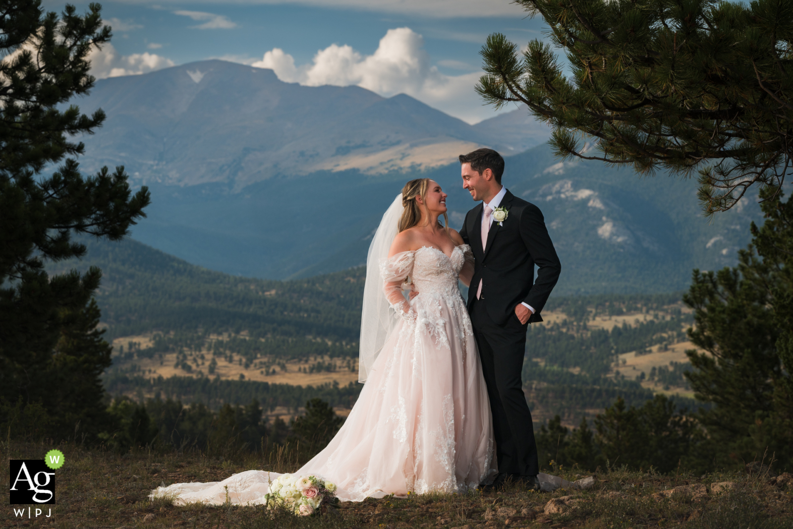 Following their wedding ceremony, a couple stands nestled amidst the rugged landscape of YMCA of the Rockies in Estes Park, Colorado, the mountains providing a grand, natural frame for their joy.