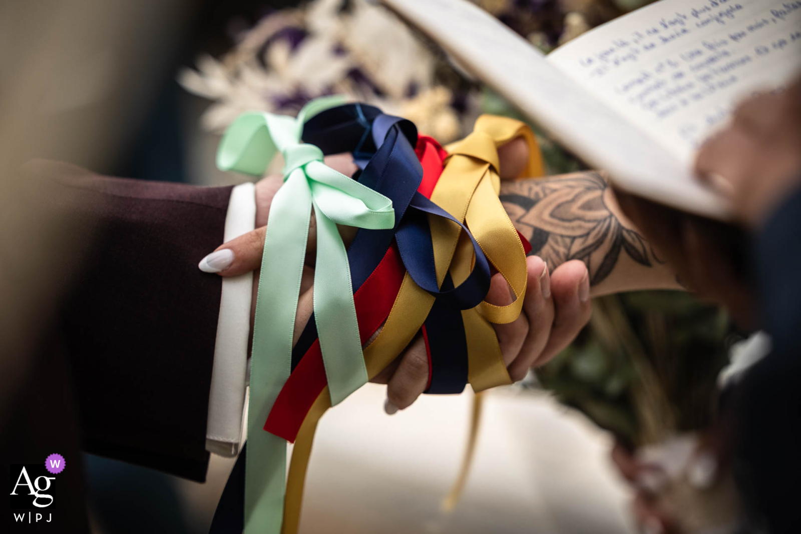   In Aix les Bains, Savoie, France, the hands of the bride and groom are joined during the ribbon ceremony, capturing a wedding tradition with meaningful color and texture.