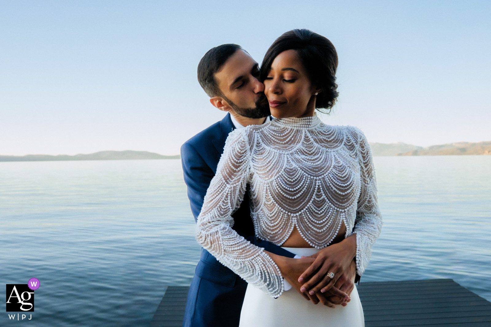   Along the peaceful shoreline of South Lake Tahoe, the couple shares a tender kiss, their embrace framed by delicate lace and the lakeside scenery in an intimate portrait.