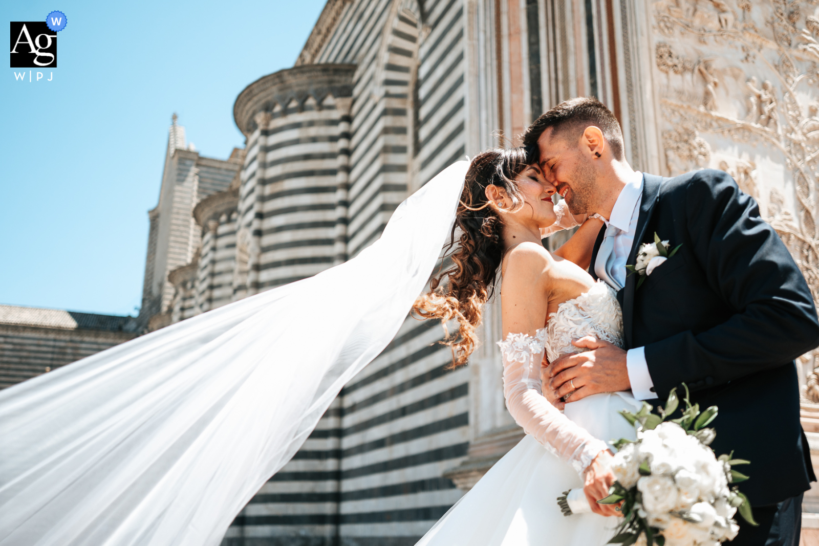   With Orvieto Cathedral as a dramatic backdrop, the groom draws the bride close in a windy square, her veil billowing gracefully into the air, evoking movement and emotion.