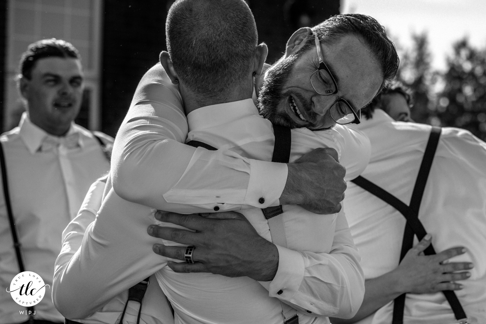 Fotografia de casamento em Alberta mostrando o padrinho abraçando o noivo no The Estate, Spruce Grove