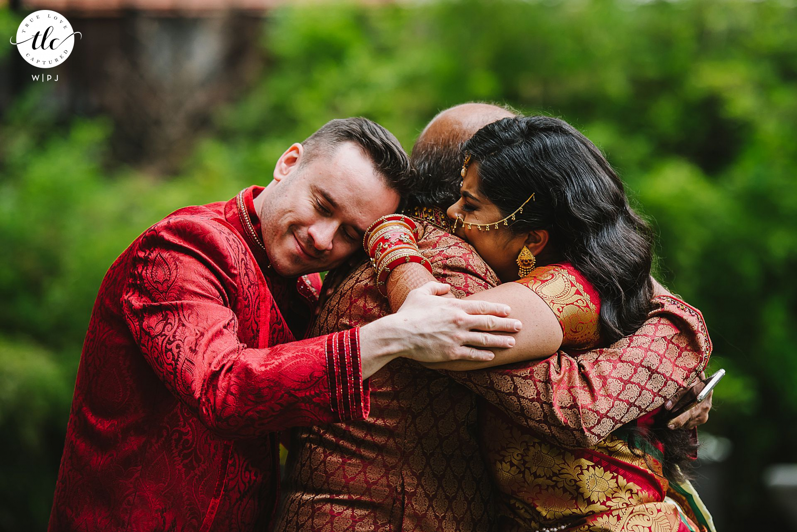 Flushing Town Hall, Queens NY documentary wedding image of a Bride and Groom embracing the Bride's father 