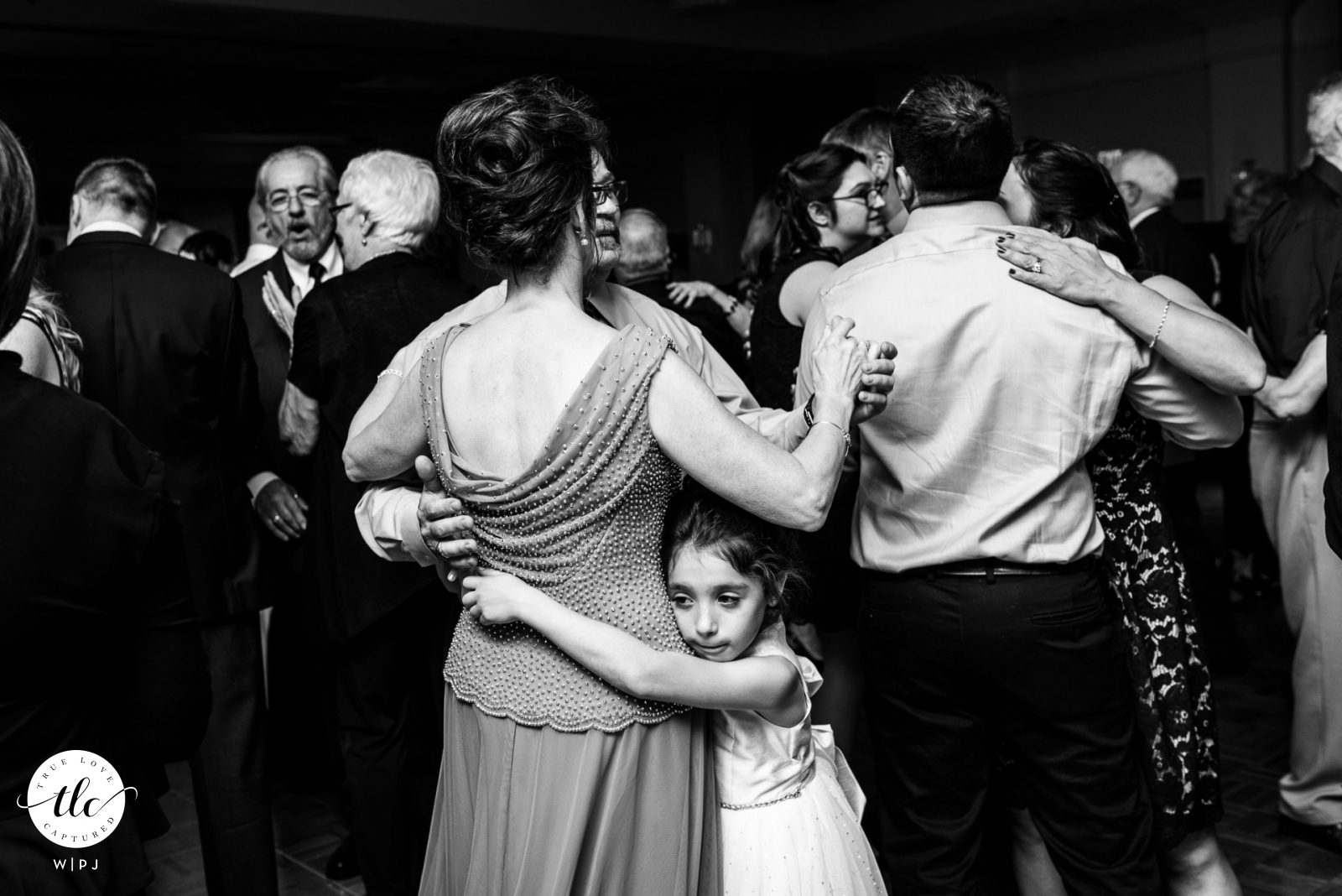 Boston Marriott, Peabody MA documentary wedding image of a young girl hugging the leg of her grandmother during a wedding dance