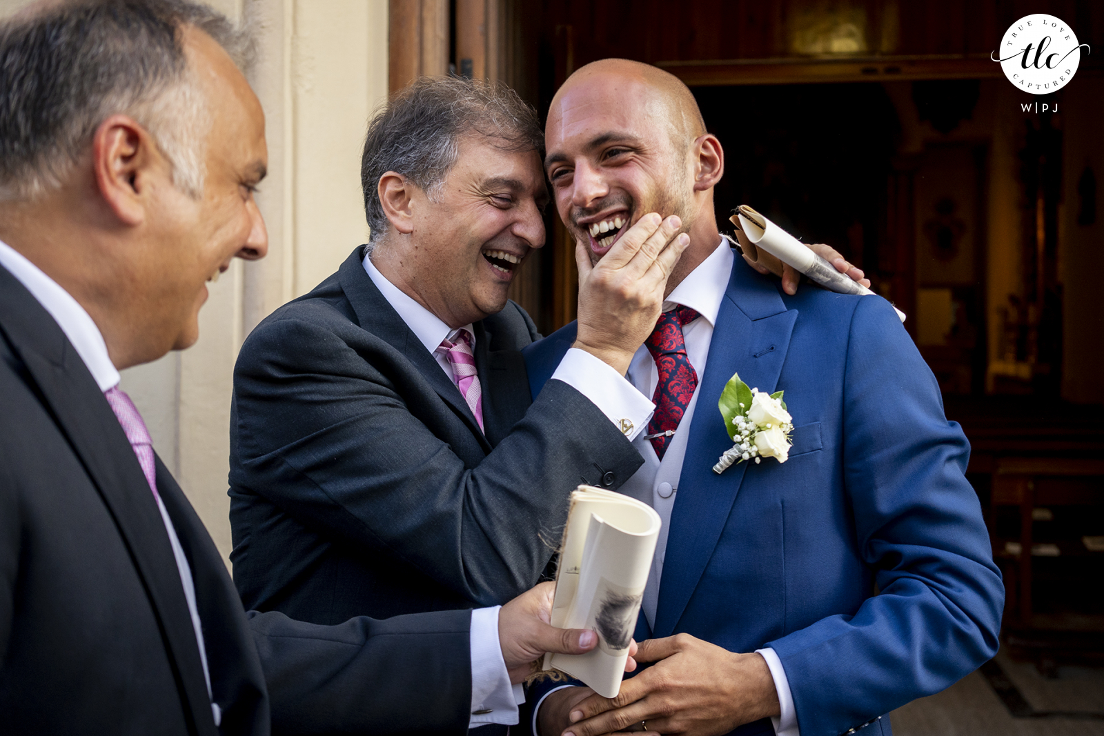 Um relato verdadeiro de emoções cruas em uma imagem do dia do casamento na Espanha capturada por um fotógrafo documental de casamento em Miramar, Málaga, mostrando o noivo recém-casado recebendo carinho dos homens