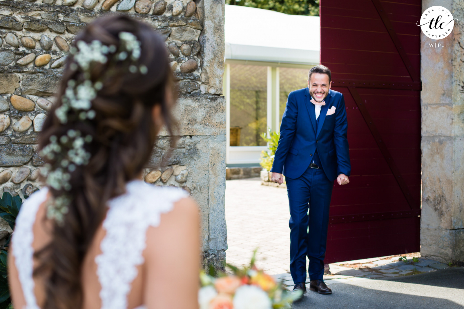 Este momento auténtico y emotivo del día de la boda en Francia desde Domaine de Grand Maison en Oyster Saint Oblas fue grabado por un fotógrafo de bodas documental que muestra al novio emocionado viendo a la novia por primera vez.