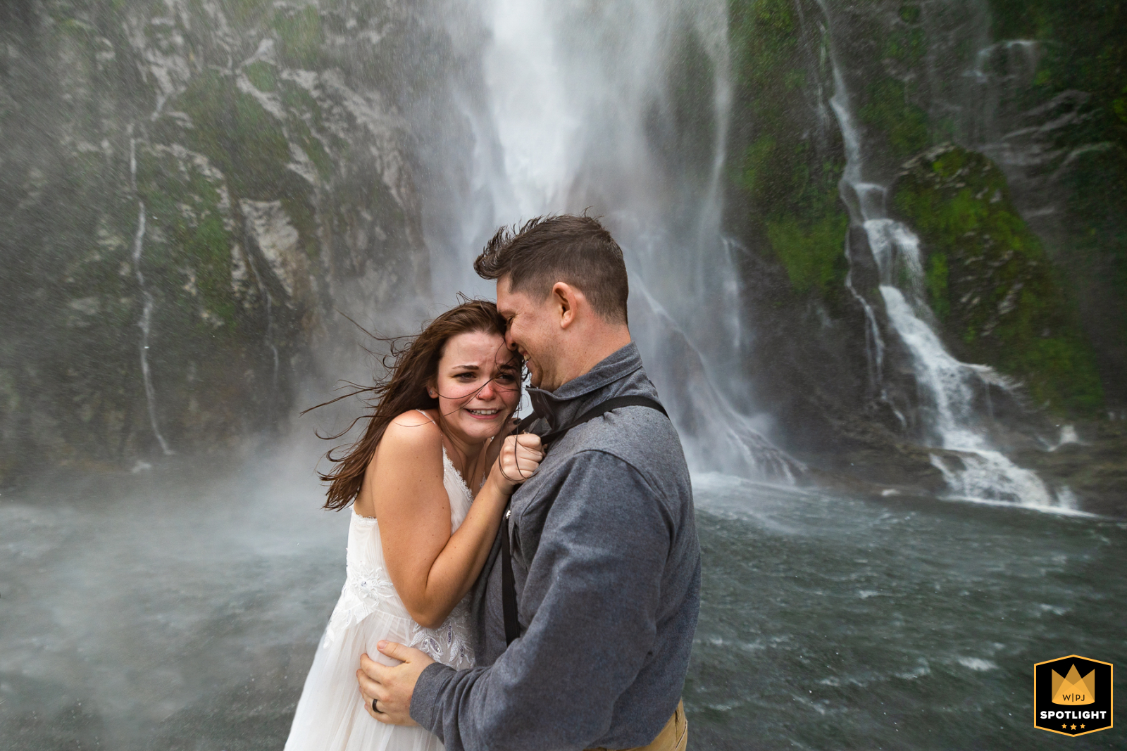 Wedding couple endures freezing waterfall at Milford Sound, New Zealand.