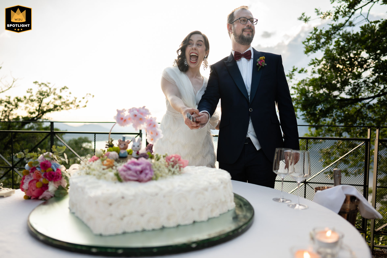 Bride's Playful Cake-Cutting at I Due Roccoli Wedding At I Due Roccoli, Iseo, the bride playfully jokes while cutting the wedding cake, filling the moment with laughter and joy.