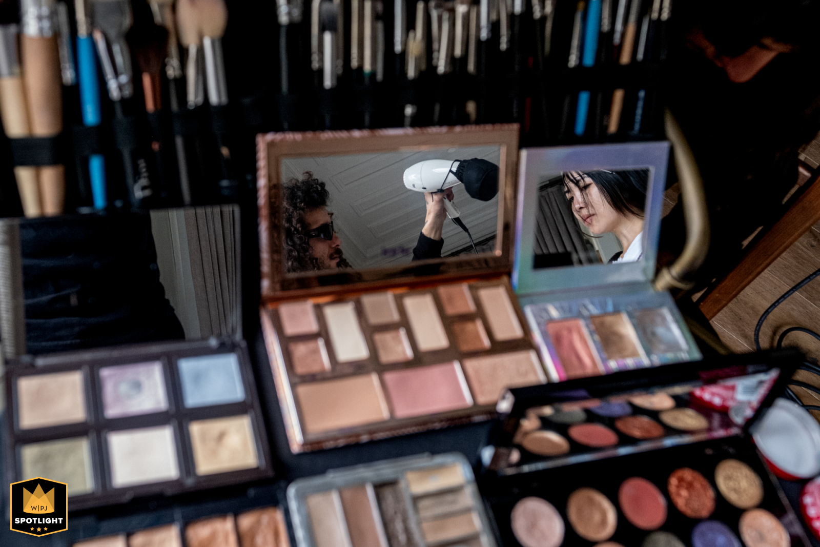 Istanbul Six Senses: Reflection of Beauty Prep At Six Senses Kocataş Mansions Istanbul, a makeup accessory reflects a hairdresser with long curly hair and sunglasses, alongside the bride, surrounded by makeup.