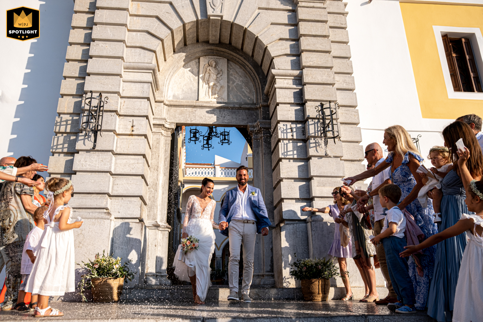 Simi Panormitis: Confetti Showered Couple At Simi Panormitis Monastery, a bride and groom hold each other as they leave the church, showered with confetti by guests.