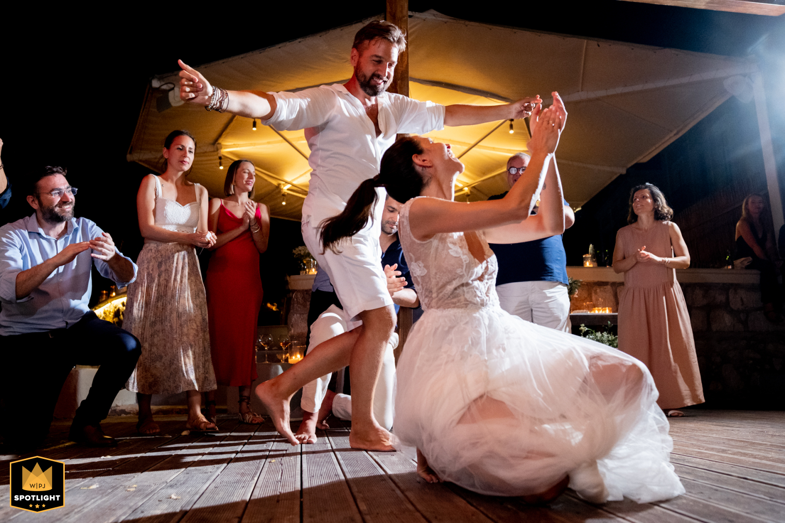 Symi Restaurant Wedding Venue: Barefoot Greek Dance At a restaurant by Sean in Symi, the bride and groom dance barefoot to traditional Greek music, captured by a WPJA photographer.
