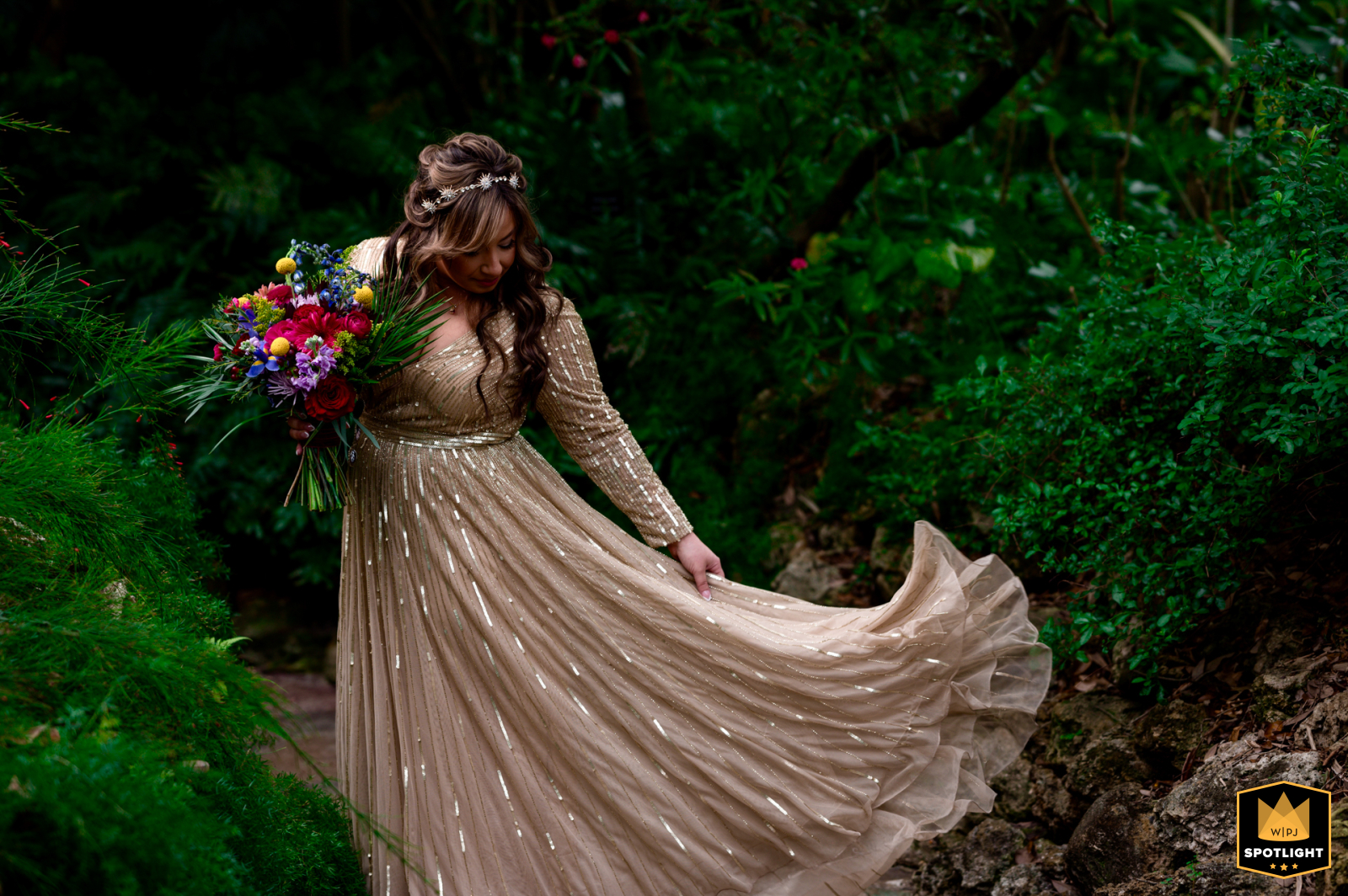 Sunken Gardens: Bride Adjusts Dress in Greenery At Sunken Gardens St. Petersburg, Florida, a bride stands alone, adjusting her dress amidst green foliage before posed portraits.