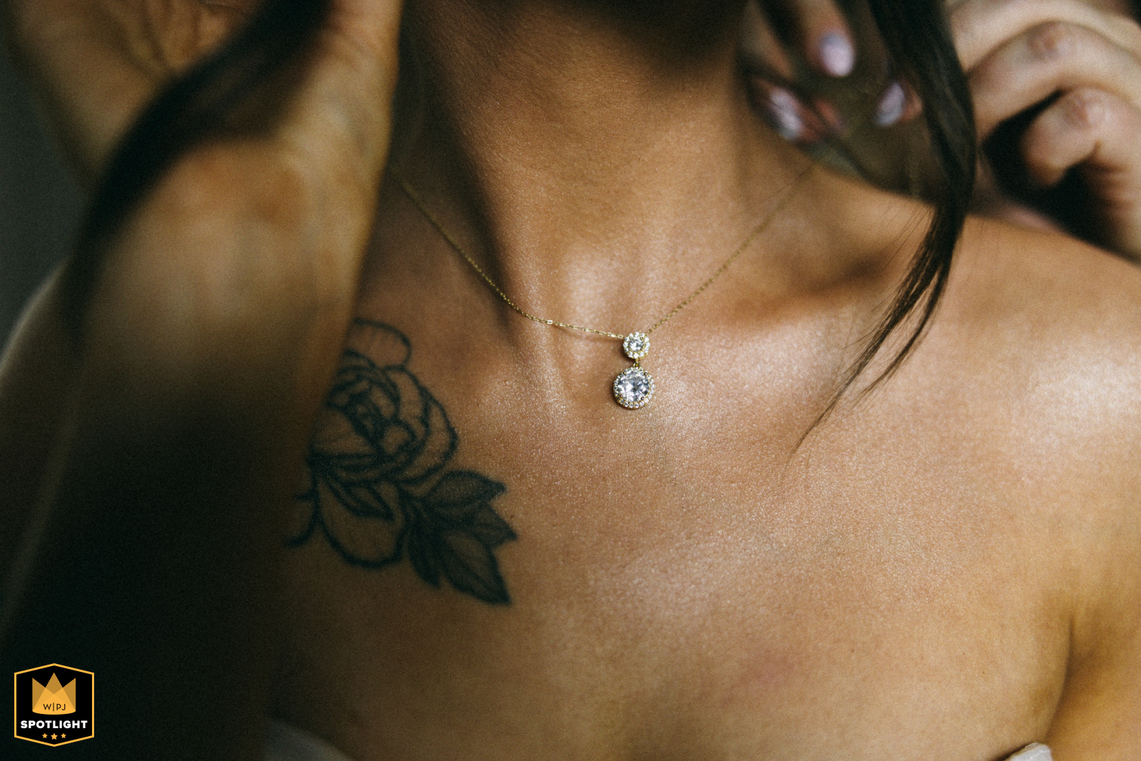 At a hotel in West Pomeranian, Poland, a bridesmaid fastens a necklace on the bride, a tight shot showing her tattooed skin and clasping hands.