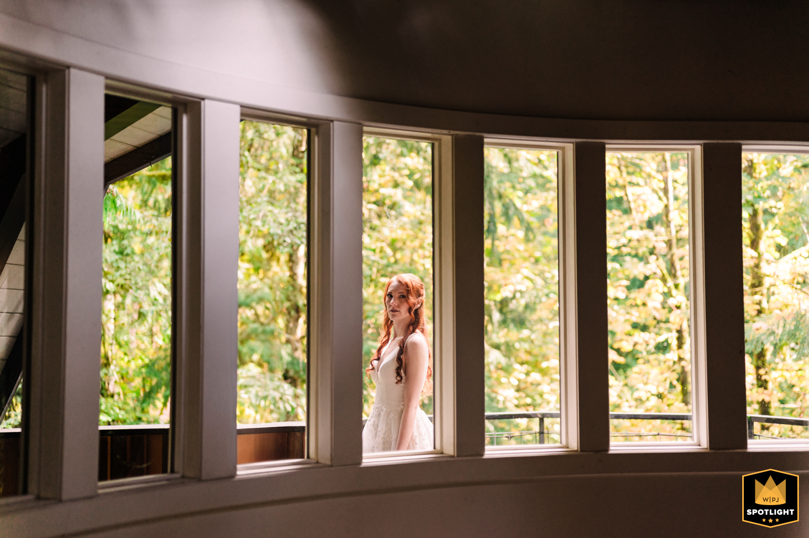 Vertical Windows Frame Bride at Cabin in Deming, WA At a cabin in Deming, WA, a bride stands on the balcony, looking inward through a series of repeating vertical windows.