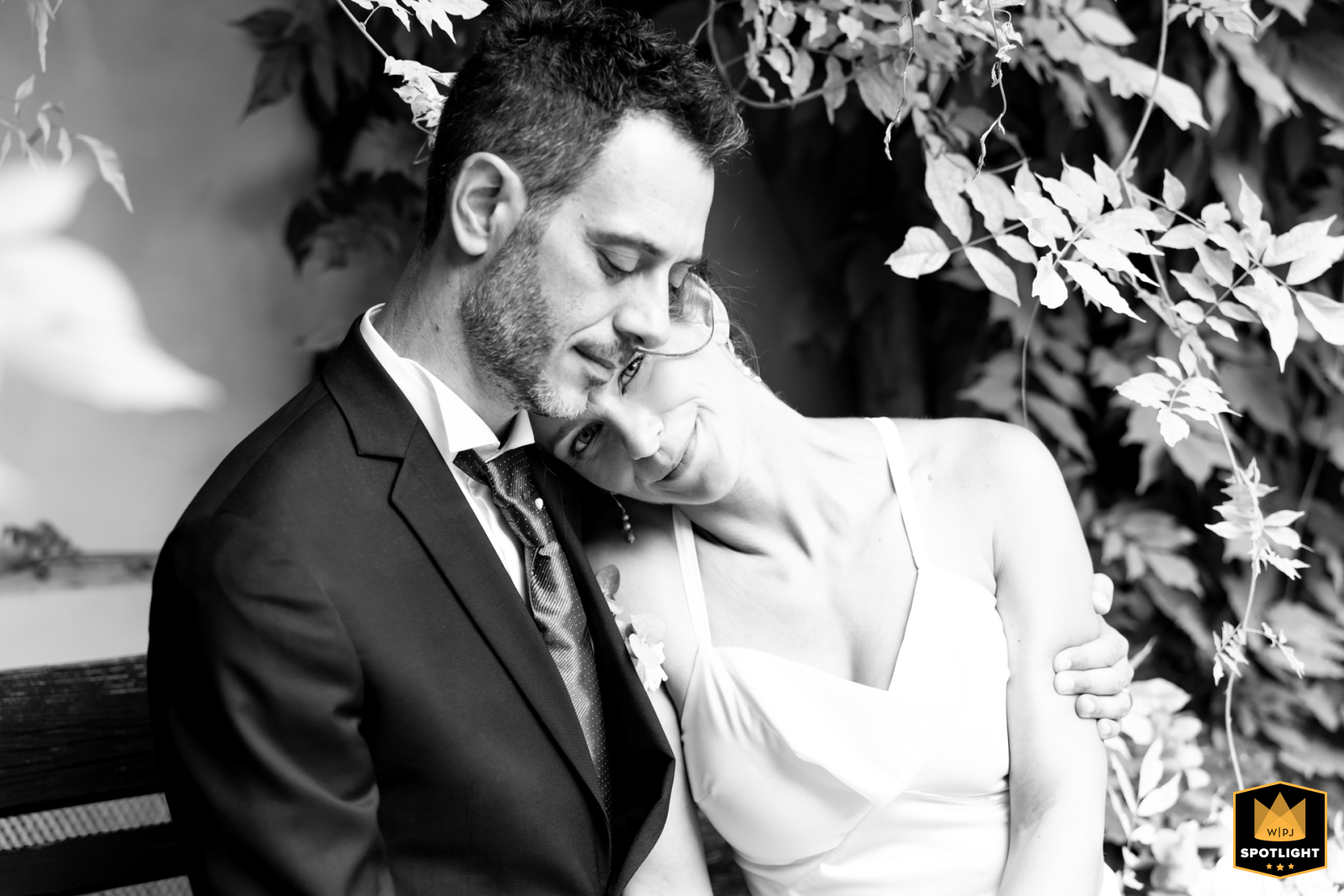 In the City Centre Garden of Forlì, Italy, the bride leans gently on the groom’s shoulder, her candid gaze captured in a black and white portrait during their romantic wedding session.  