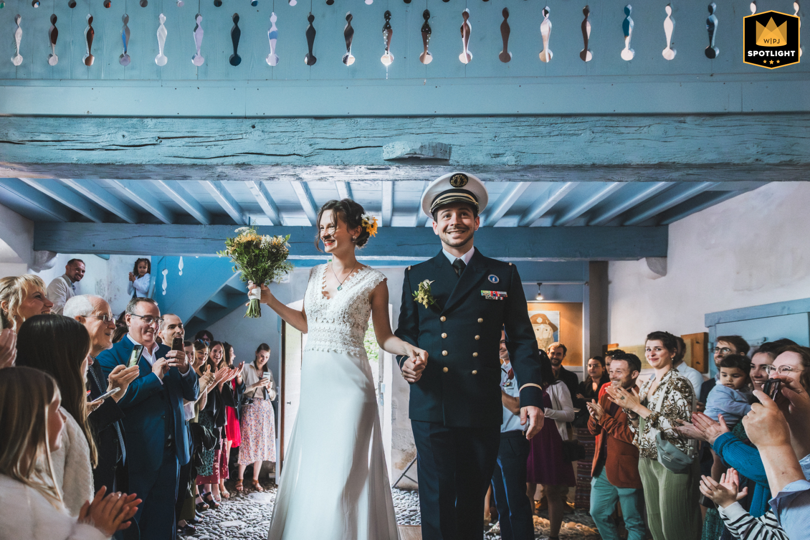 The bride and groom enter the deconsecrated chapel of Borce for their ceremony. Their guests cheer, creating a joyful and memorable atmosphere for their wedding in France.