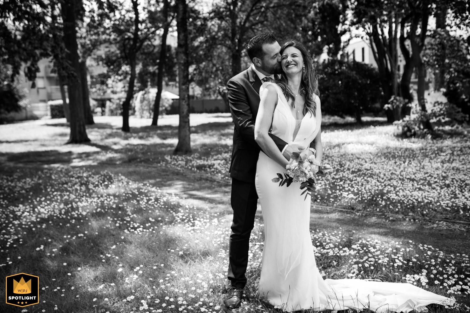 A black-and-white photo from Saint-Jean, France, captures the bride and groom. He embraces her from behind, a scene of quiet intimacy that showcases the couple's strong bond.