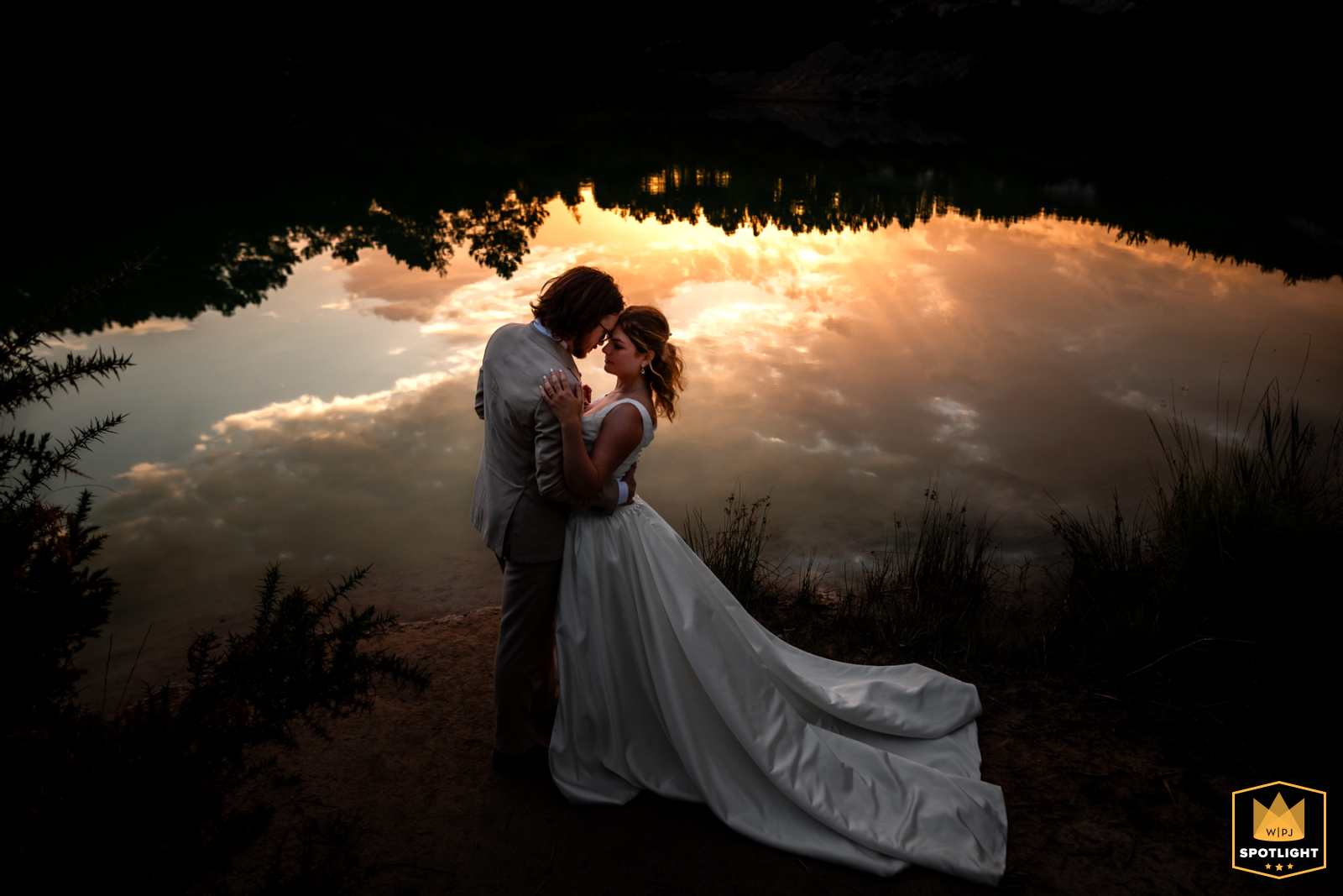 Charente, France: A couple stands by a lake at sunset, bathed in the warm, romantic light.