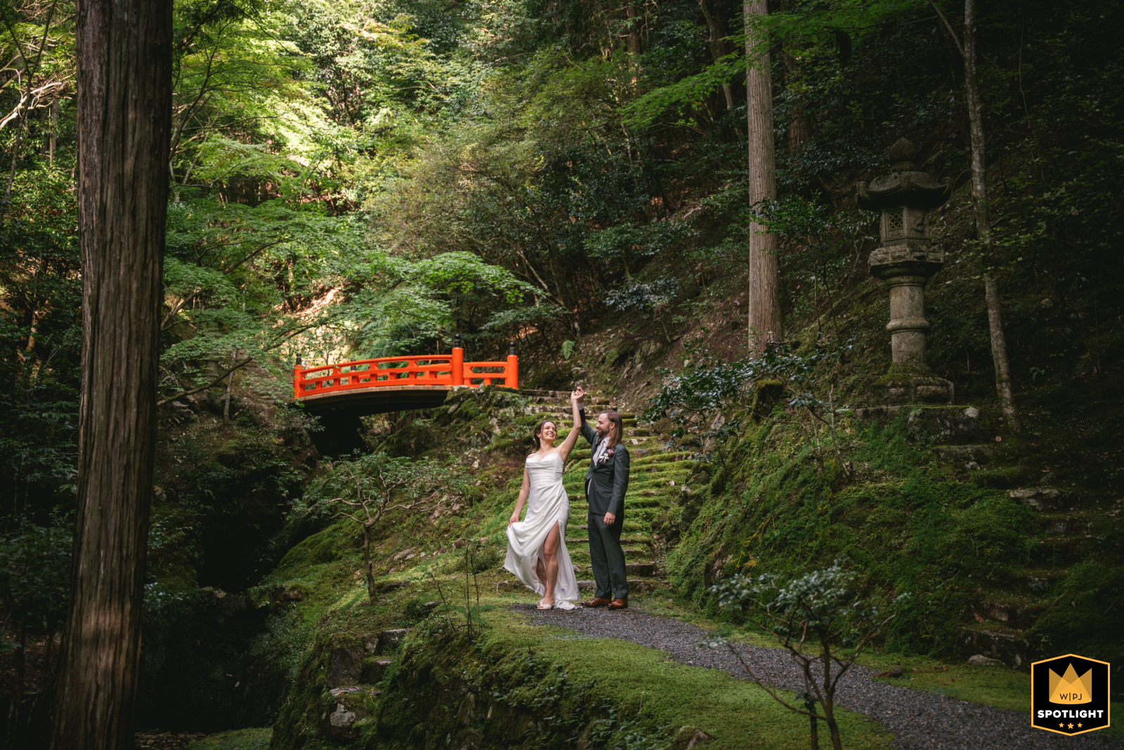 In Kyoto, Japan, a couple dances gracefully in a lush forest, framed by the vibrant greenery and an ancient Japanese bridge, creating a romantic, timeless scene that blends natural beauty with tradition.