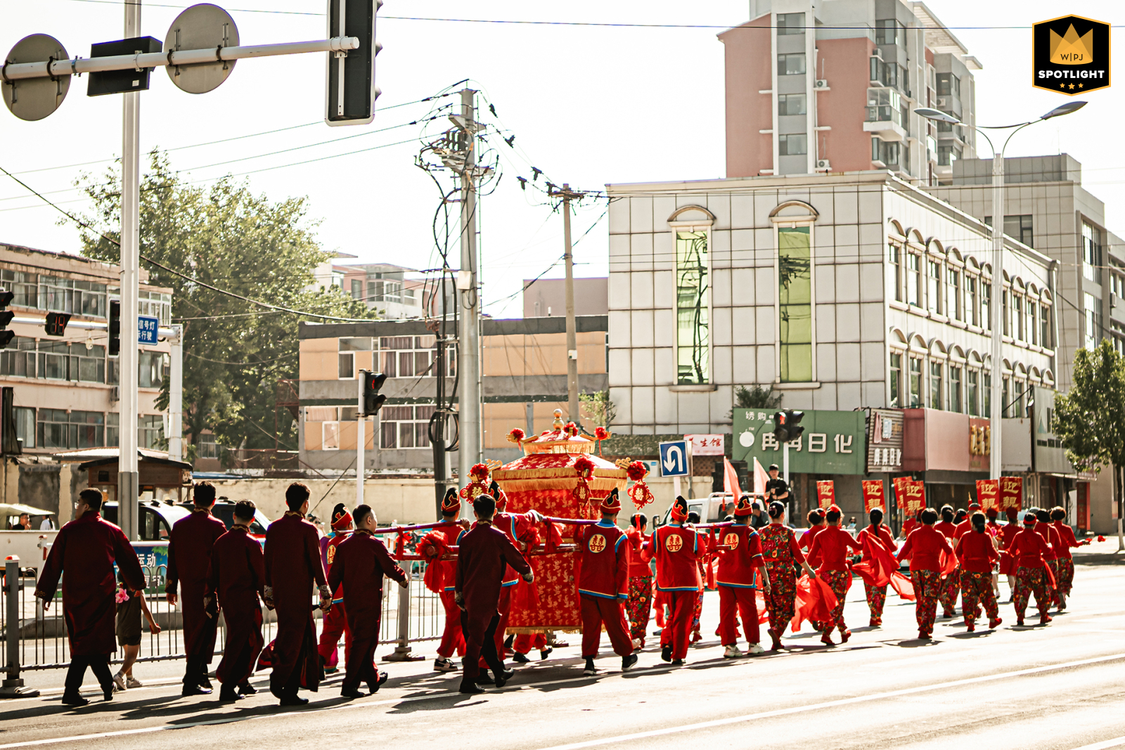   Along the wedding procession route in Shandong, China, the traditional bridal sedan chair is carried, adding vibrant color and cultural tradition to the festivities.