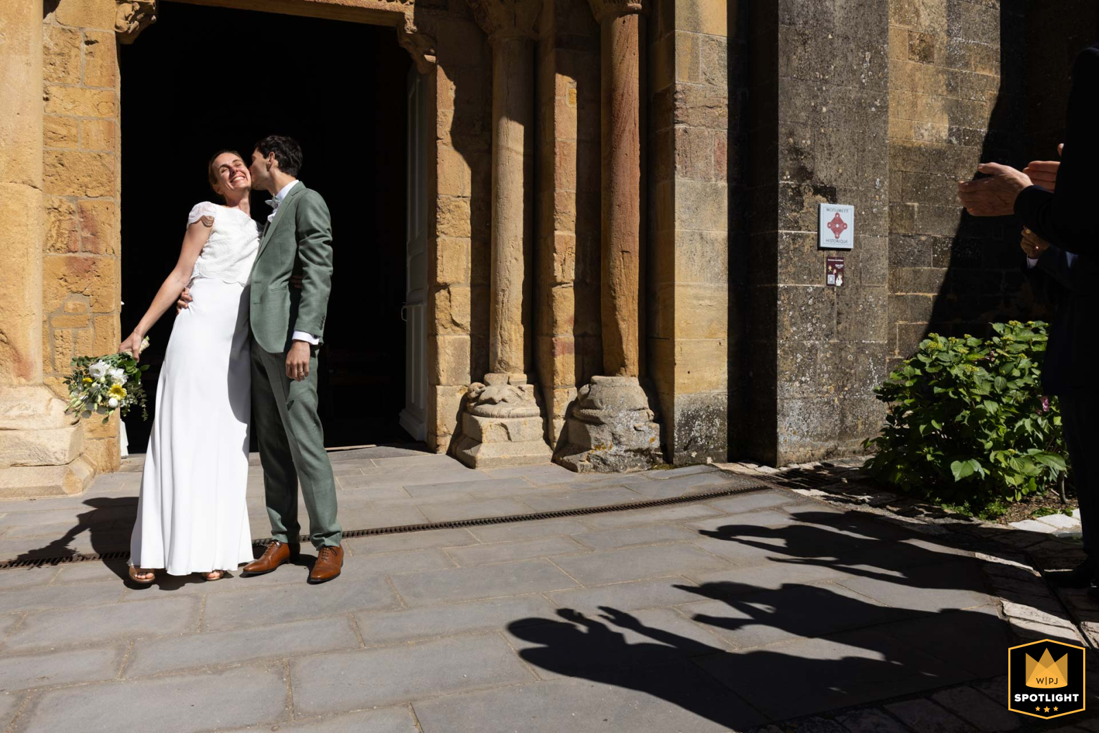   Silhouetted figures emerge dramatically from the church after the ceremony in Anzy le Duc, Bourgogne, France, creating a striking shadow play against the historic backdrop.