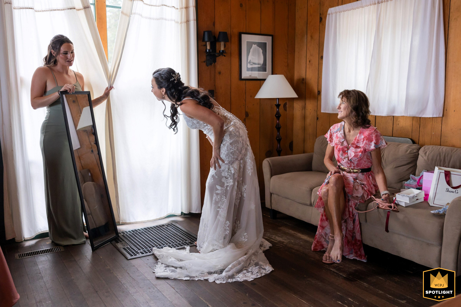   In South Lake Tahoe, CA, the bride leans in with a warm, curious smile, admiring her reflection while loved ones look on with quiet pride, sharing in her joyful anticipation.