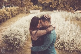 A man and woman hug one another in a garden in Genoa during their engagement photoshoot by a Liguria photographer.