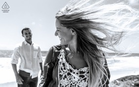 Maceió, Alagoas portrait e-session created as the woman smiles while her fiance is watching, and her hair is flying