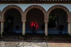 True Love Engagement Posed Portrait at the Patios de Viana in Córdoba capturing a couple under 3 arches with a red backlight spot